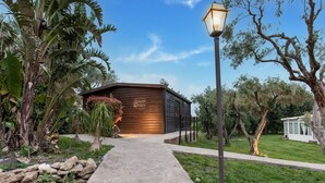 A wooden building with a stone pathway leading to it, surrounded by lush greenery and a clear sky. - Holiday Home near Mount Etna Views (Carlentini)