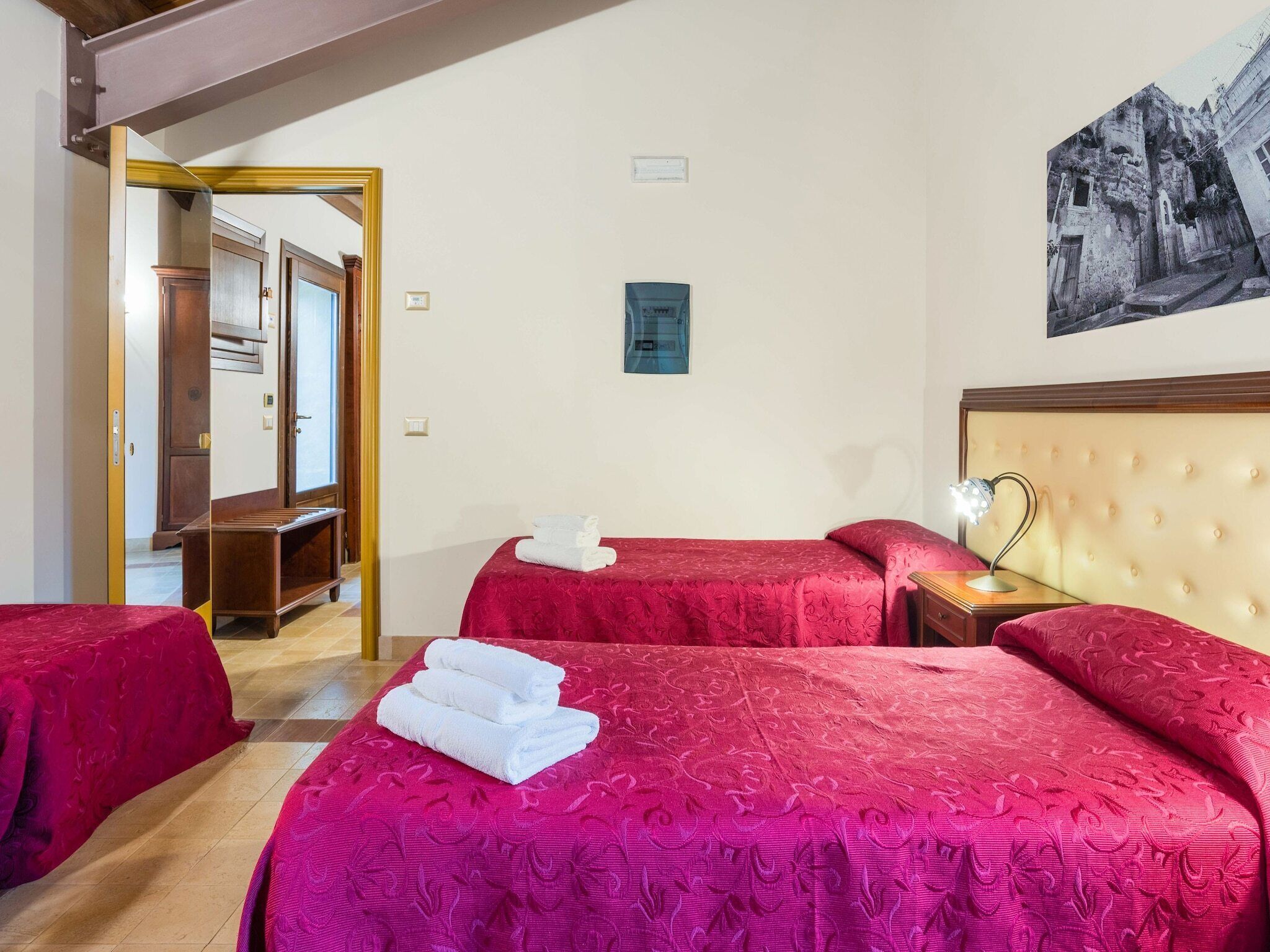 Une chambre d’hôtel avec deux lits, une tête de lit en bois, une table de chevet et un tableau au mur.