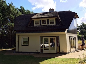A two-story house with a thatched roof, large windows, and a garage door.