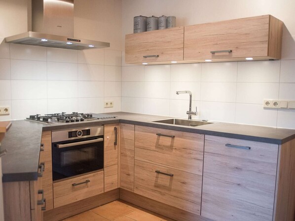 A modern kitchen with a gas stove, oven, and stainless steel sink.