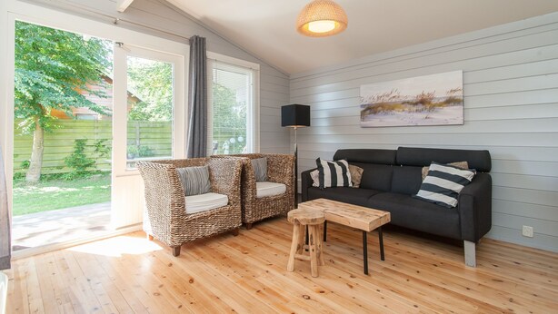 A cozy living room with a sofa, two wicker chairs, a wooden coffee table, and a painting on the wall.