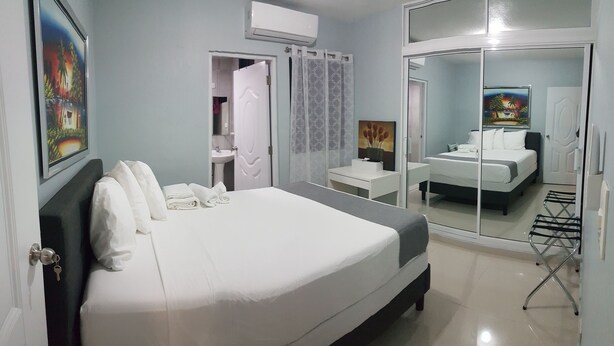 Ein Hotelzimmer mit einem großen Bett, einem Badezimmer mit Dusche und Waschbecken sowie einem Spiegel, der den Raum widerspiegelt.