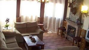 A cozy living room with a fireplace, comfortable seating, and a deer head mounted on the wall.