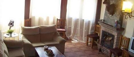 A cozy living room with a fireplace, comfortable seating, and a deer head mounted on the wall.