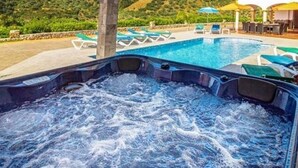 A hot tub with a pool and lounge chairs in a sunny outdoor setting.