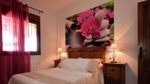 A bedroom with a bed, two bedside tables with lamps, a wooden headboard, a window with curtains, and a wall with a poster.