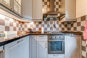 A kitchen with white cabinets, a black countertop, and a stainless steel range hood.