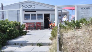 Un bâtiment dont la façade porte l’inscription « NOORD », caractérisé par un design simple et moderne, avec un toit plat et de grandes fenêtres.