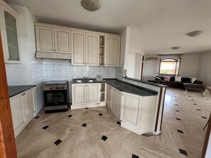A kitchen with white cabinets, a stove, and a sink.
