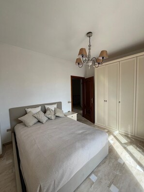 Ein Schlafzimmer mit Bett, Kleiderschrank und einer Kandelaber.