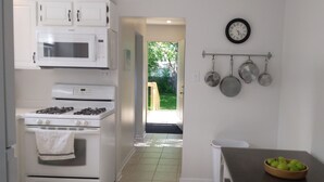 Une cuisine avec des armoires blanches, une cuisinière, un four à micro-ondes et une horloge au mur.