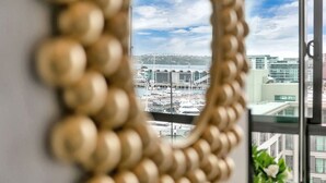 Une vue sur une marina, avec des bateaux et un pont, telle qu’on la voit à travers une fenêtre ornée d’un rideau de perles dorées.