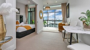 Une chambre d’hôtel moderne dotée d’un lit, d’un coin repas et d’un balcon offrant une vue sur la ville.
