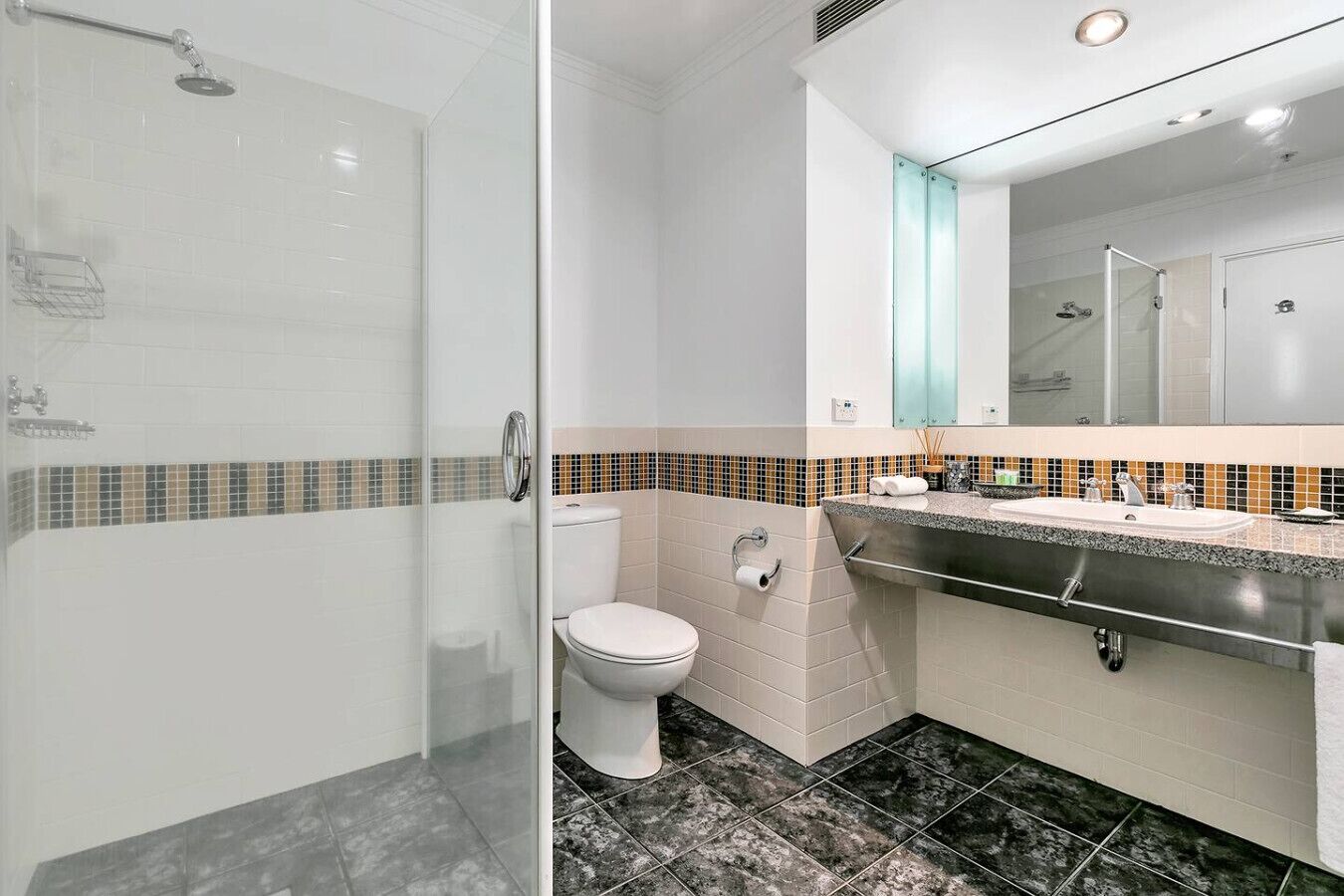 Une salle de bain moderne avec une douche à parois de verre, des toilettes et un lavabo avec un miroir au-dessus.