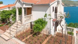 A coastal building with a red-tiled roof, a balcony, and a view of the sea. - Apartments Marko - Two Bedroom Apartment with Terrace with Sea View (Okrug Donji)