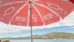 A round table with four chairs and a red umbrella with white designs, overlooking a body of water and hills. - Apartments Marko- Superior Two Bedroom Apartment with Terrace and Sea View (Okrug Donji)