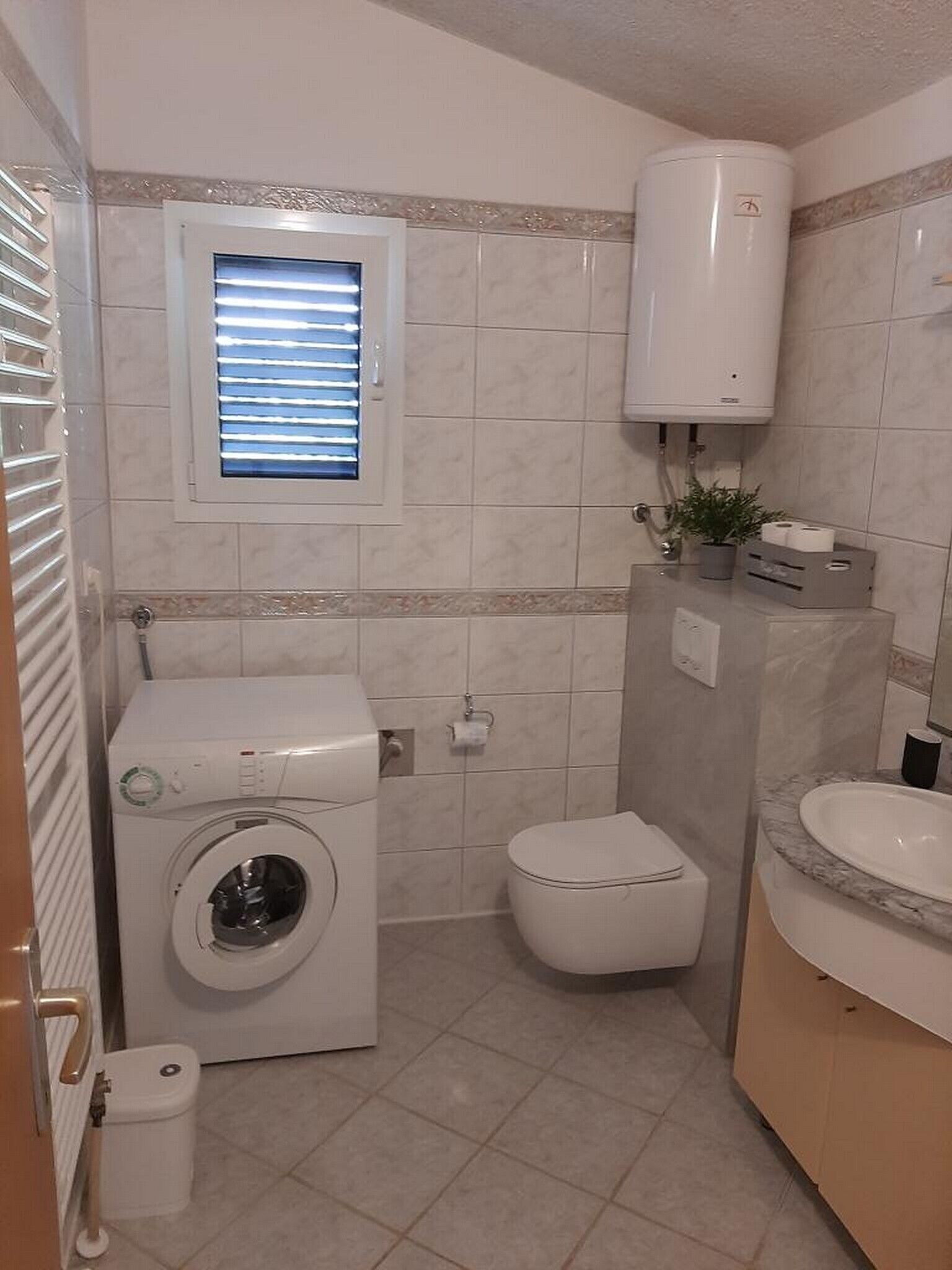 Une petite salle de bain équipée d’un lave-linge, de toilettes et d’un lavabo.