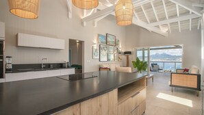 Une cuisine moderne dotée d’un grand îlot central, de luminaires suspendus et offrant une vue sur la ville.