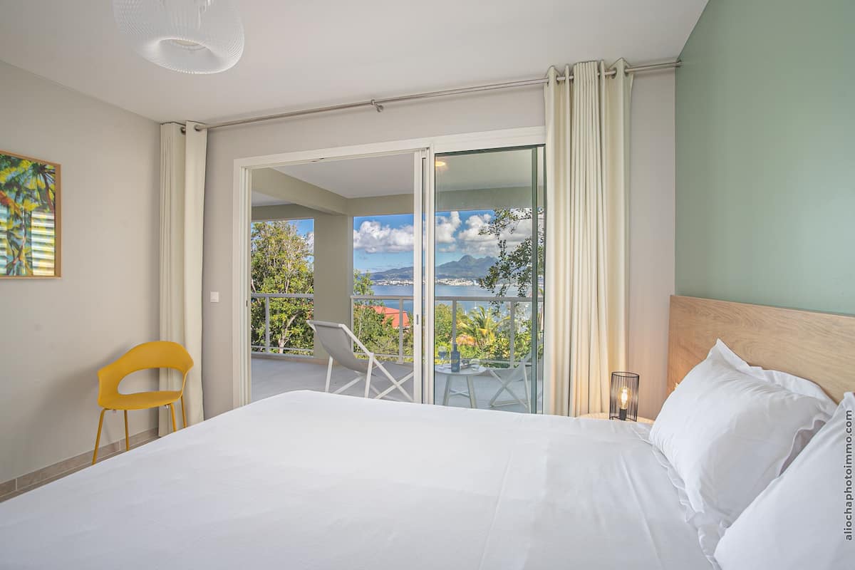 Habitación de hotel con cama, una silla, una mesa y balcón con vistas a las montañas.