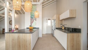 Une cuisine moderne dotée d’un îlot central, de luminaires suspendus et donnant sur l’espace repas.