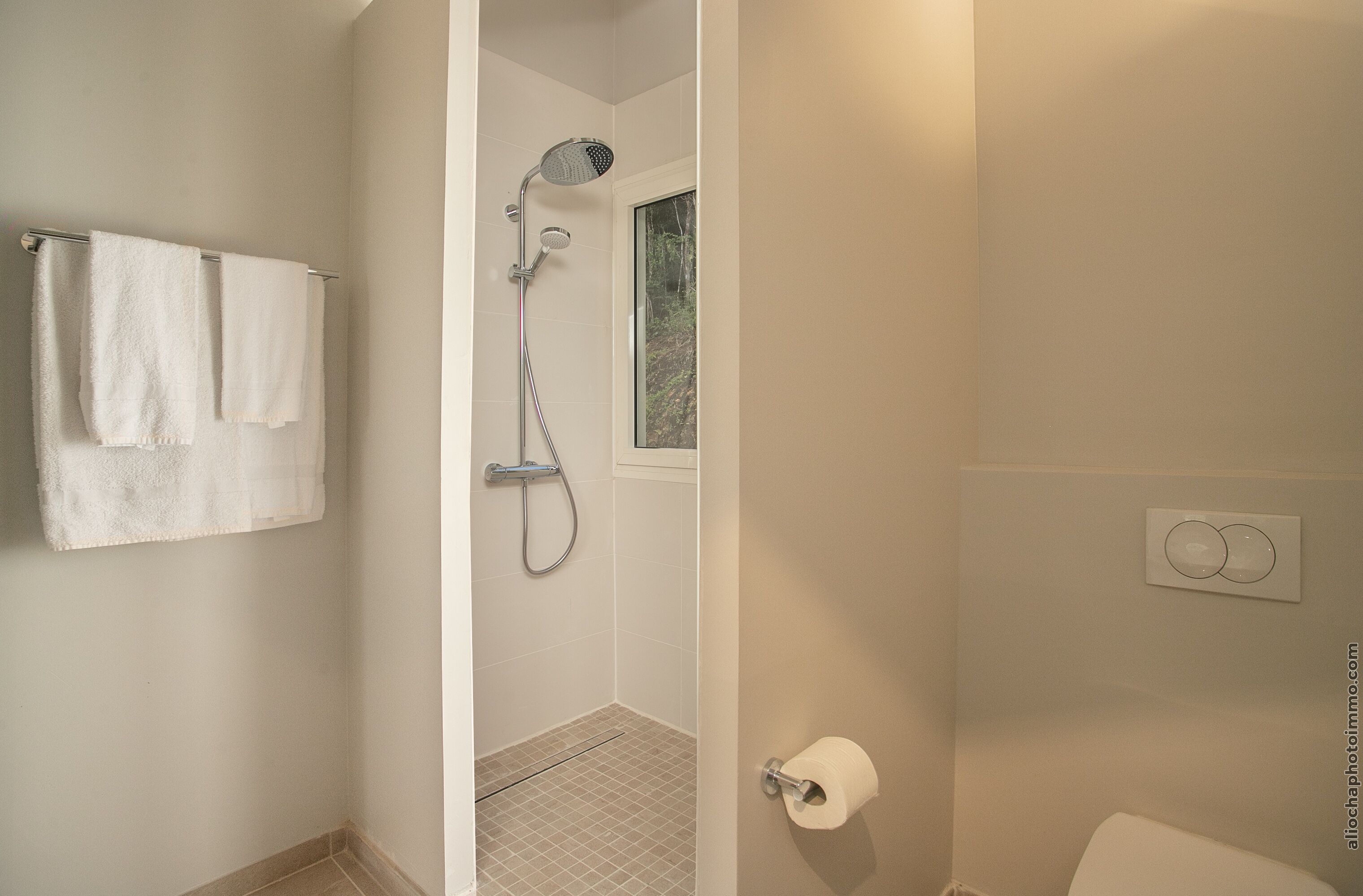 A bathroom with a shower, a toilet, and a towel rack with two towels.