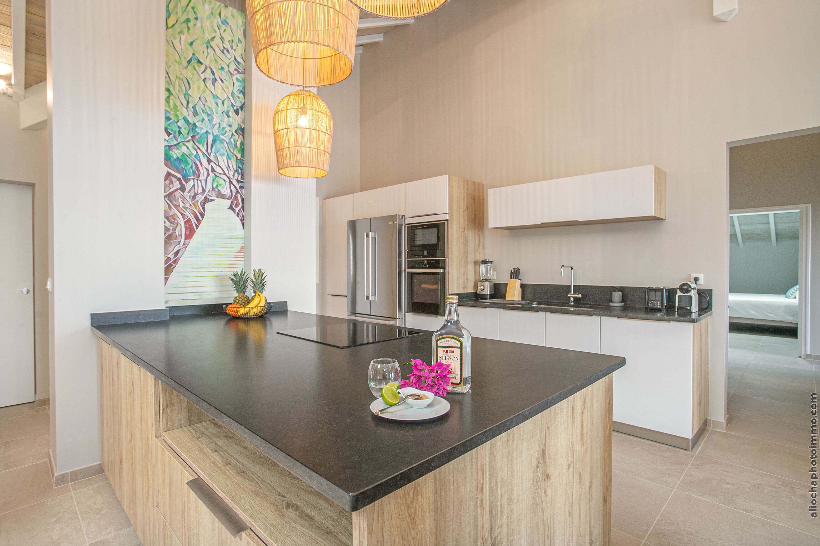 A modern kitchen with a central island, stainless steel appliances, and a decorative painting on the wall.