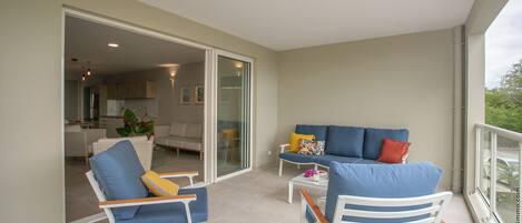 Een ruim balkon met een bank, stoelen en een eettafel.