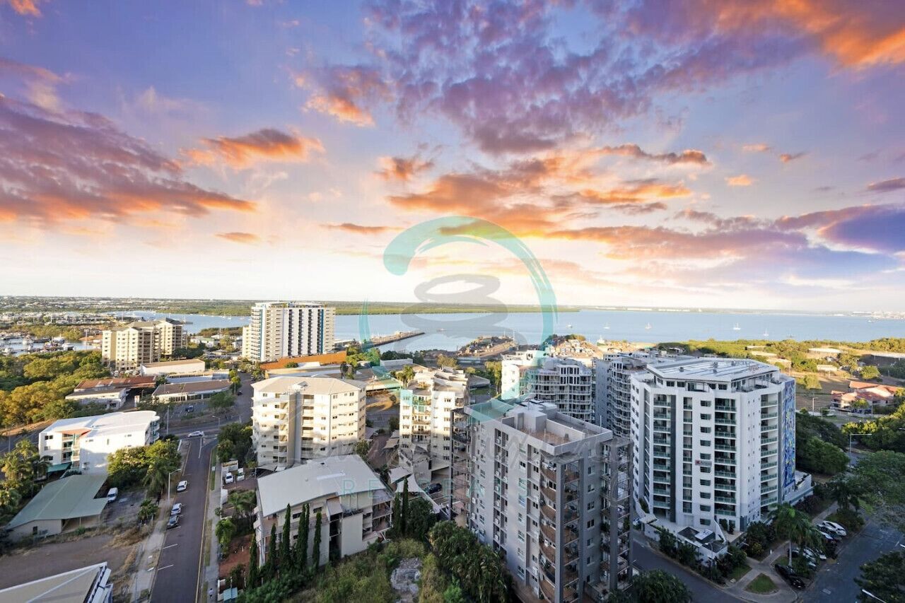 A high-rise building complex with multiple residential and commercial structures, a waterfront view, and a clear sky.