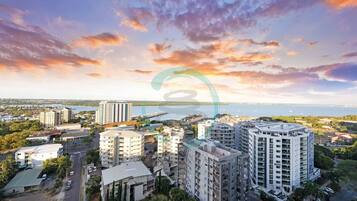 A high-rise building complex with multiple residential and commercial structures, a waterfront view, and a clear sky.