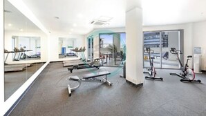 A modern gym with cardio machines, weight benches, and exercise bikes.