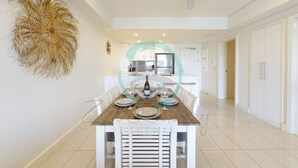 A modern dining area with a wooden table set for six, white chairs, and a ceiling fan.