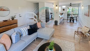 Ein modernes Wohnzimmer mit einem grauen Ecksofa, einem Couchtisch und einem Essbereich mit Tisch und Stühlen.