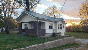 Une maison à deux étages, avec des fondations en briques et une véranda couverte.