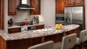 A kitchen with wooden cabinets, a stainless steel refrigerator, a microwave, and a granite countertop. - Beautiful Resort in Vail Colorado (Vail)