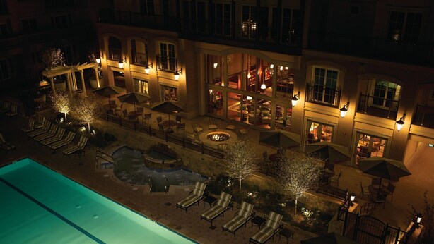 A rooftop pool area with lounge chairs and umbrellas, surrounded by a building with multiple balconies and lit windows. - Beautiful Resort in Vail Colorado (Vail)