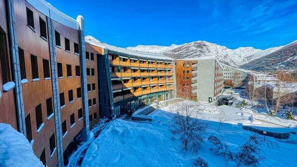 A modern building with multiple floors, a covered outdoor area, and snow-covered surroundings.