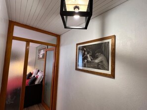 A hallway with a wooden door frame, a black storage unit, and a framed black and white photograph on the wall.
