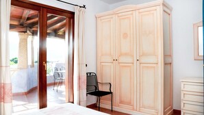 Une chambre à coucher comprenant un lit, une armoire, une chaise et un balcon avec une table et des chaises.