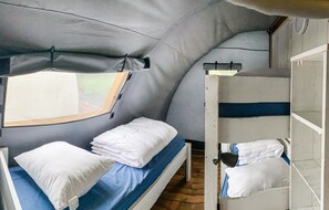 Cozy accommodation with a bunk bed and single bed, featuring a rustic wooden ceiling and brick floor.