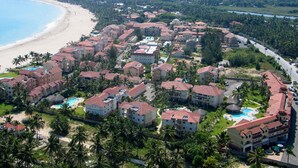 Un resort con varias edificaciones, playa y zona de piscina.