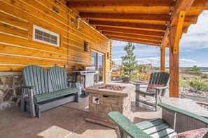 A wooden cabin with a stone fire pit, outdoor seating, and a view of the surrounding landscape. - Rustic Retreat: Unplug and Unwind (Mack)