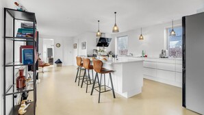 A modern kitchen with a central island, bar stools, pendant lighting, and a large window. - Gorgeous home in Sunds with kitchen (Sunds)