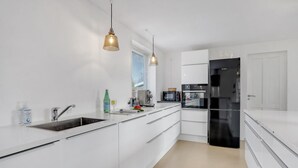 A modern kitchen with white cabinetry, a stainless steel sink, a black refrigerator, and a coffee maker. - Gorgeous home in Sunds with kitchen (Sunds)