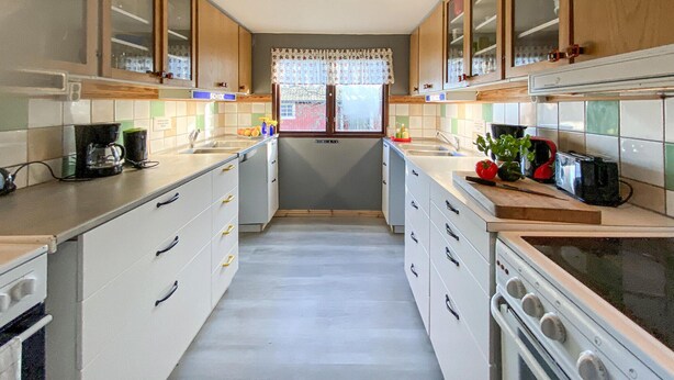 Una cocina estrecha con armarios de madera, una isla central y vistas al exterior a través de una ventana.