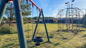 Un parque infantil con columpios, un neumático colgante y una estructura metálica para escalar.