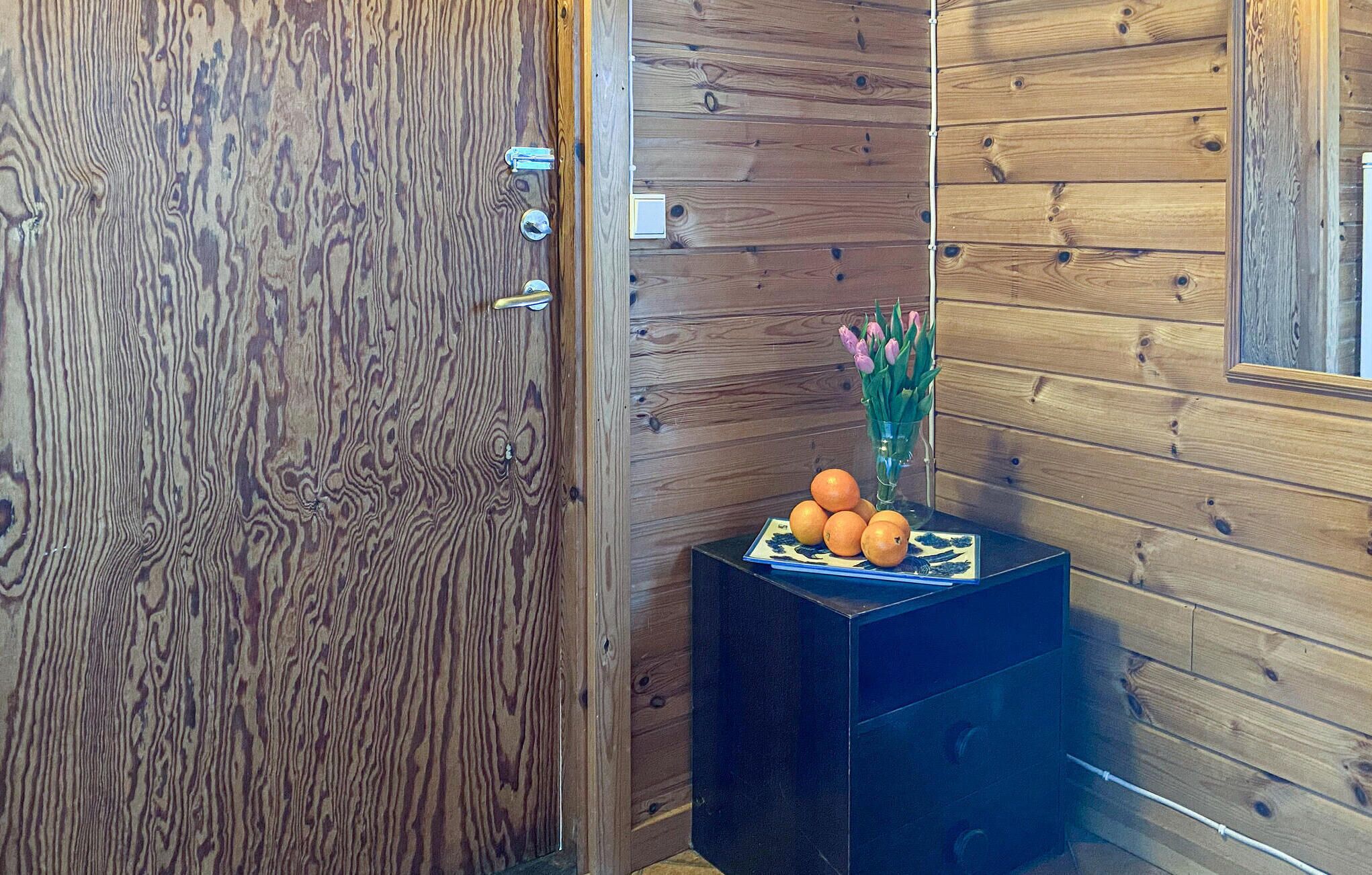 Une porte en bois avec une poignée en métal et un petit objet rectangulaire accroché au mur à côté.