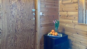 Una puerta de madera con un picaporte de metal y un objeto rectangular pequeño en la pared a su lado.