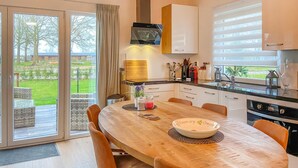 Een moderne keuken met een grote eettafel, een inbouwoven en uitzicht op de omgeving.