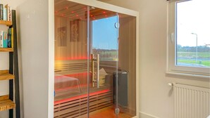 Een moderne kamer met een glazen scheidingswand, een houten bank, een radiator en een raam met uitzicht op de omgeving.