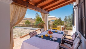 A covered outdoor dining area with a table set for two, a view of the countryside, and a wooden pergola structure. - Casa La Era Villanueva de la Concepción by Ruralidays (Málaga)